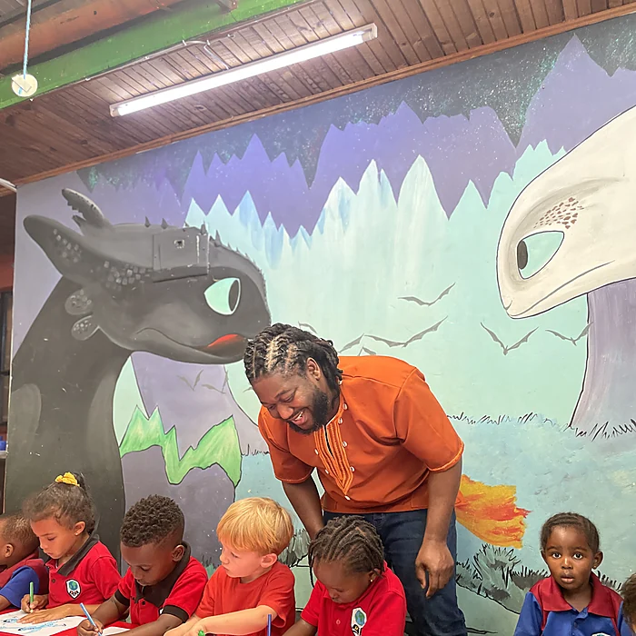 Bernard leaning over to talk with children at a classroom table